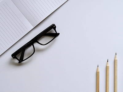 eyeglasses with black frames beside notebook and pencils thumbnail