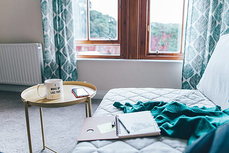 white ceramic coffee mug on top of round white steel tray near glass window with brown wooden frame thumbnail