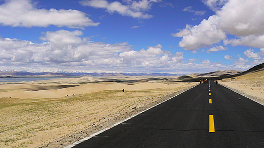 gray asphalt road in between brown sand at daytime thumbnail