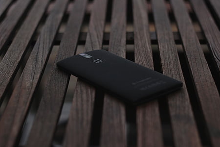 black OnePlus 1 smartphone on brown surface thumbnail