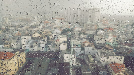 view through mirror of high rise buildings during rain thumbnail