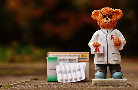 shallow focus photography of brown bear figurine on gray pavement thumbnail