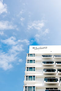 white concrete building under white and blue skies thumbnail