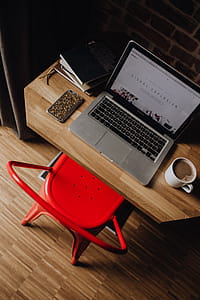 Creatives desk with laptop, camera, journals and books in front of brick wall thumbnail