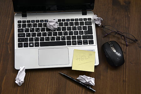 yellow sticky note on gray laptop computer beside black wireless mouse and black framed eyeglasses thumbnail