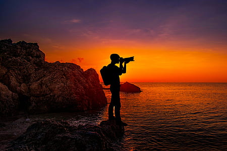 silhouette photo of a photographer standing on rack thumbnail
