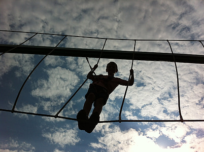 low angle photography of boy standing on hanging bridge thumbnail