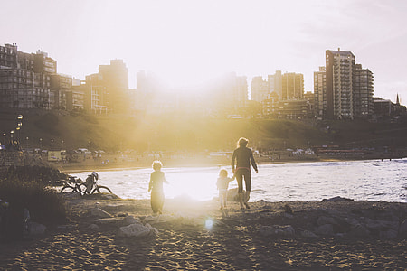 woman holding a kid while running towards body of water thumbnail