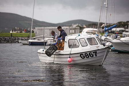 two men standing in boat on calm water at daytime thumbnail