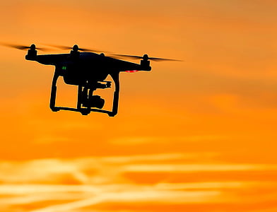 silhouette of flying quadcopter drone during golden hour thumbnail