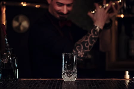 man holding cocktail shaker in front of clear glass on table thumbnail