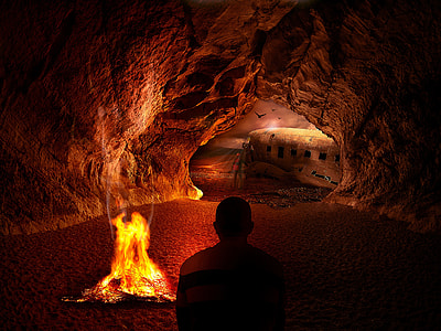 man near campfire in cave photo thumbnail