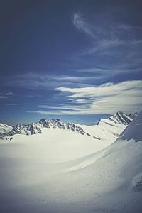 snow covered mountains under blue cloudy skies thumbnail
