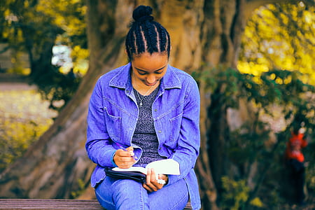 woman reading book seating on brown wooden bench chair thumbnail