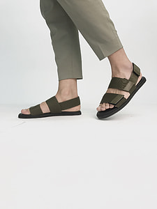 person wearing pair of black open-toe ankle-strapped sandal standing inside well lighted room thumbnail
