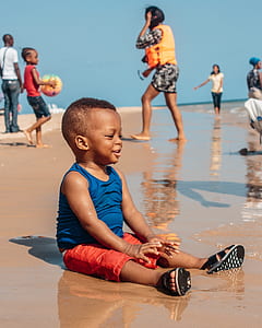 boy sitting on the seashore during daytime thumbnail