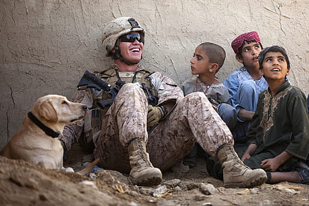 soldier sitting beside three children and adult yellow Labrador retriever thumbnail