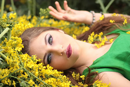 woman lying on yellow petaled flowers wearing green sleeveless dress thumbnail