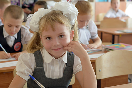 selective focus photography of girl in blue and white dress sitting on brown chair while smiling thumbnail