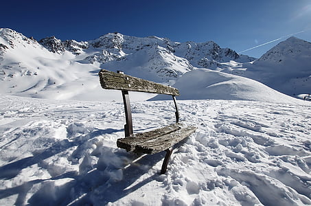 brown wooden bench on snowy ground at daytime thumbnail