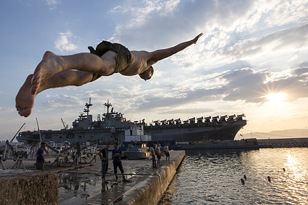 man wearing brown bottoms diving on body of water during daytime thumbnail
