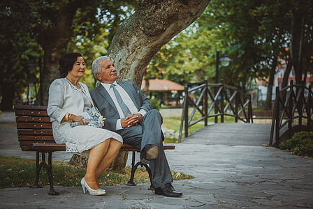 man in gray suit jacket sitting on bench beside woman in white dress thumbnail