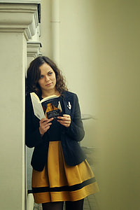 woman wearing black and yellow dress and holding a book thumbnail