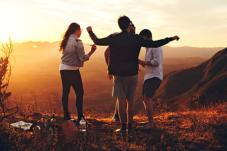 Four Person Standing at Top of Grassy Mountain thumbnail