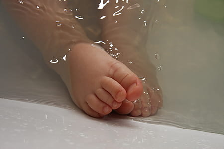 closeup photo of baby's foot on body of water thumbnail