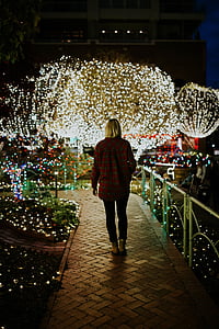 woman standing near white metal fence in front of tree at nighttime thumbnail