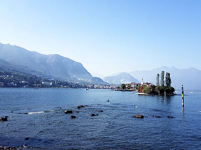 a view of mountains covered with mist across body of water thumbnail