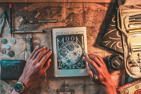 person holding pen with Moon notebook thumbnail