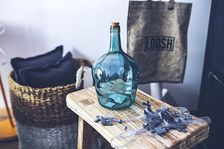 teal glass bottle on brown wooden saddle stool thumbnail