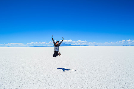 man in black and gray crew-neck sweater jumping under blue sky during daytime thumbnail