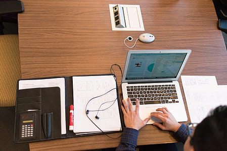 Person in Blue Dress Shirt Facing White Laptop on Brown Wooden Table thumbnail