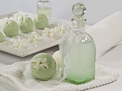clear glass bottle beside green cake pops placed on white knitted textile thumbnail
