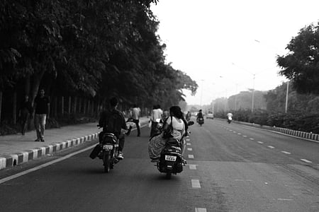 grayscale photo of people riding motorcycle beside trees thumbnail