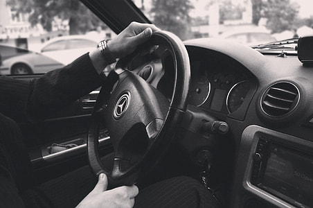 greyscale photography of person holding Mercedes-Benz steering wheel thumbnail