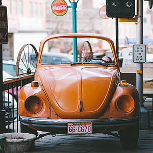 orange Volkswagen Beetle coupe park beside brown rails thumbnail