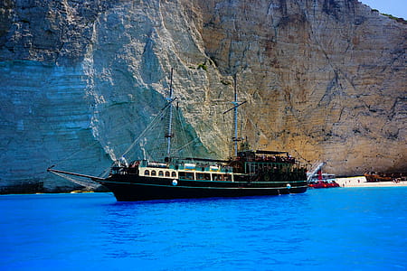 Black Ship at Sea Near Rock Formation thumbnail
