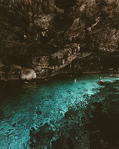several people swimming near rocks thumbnail
