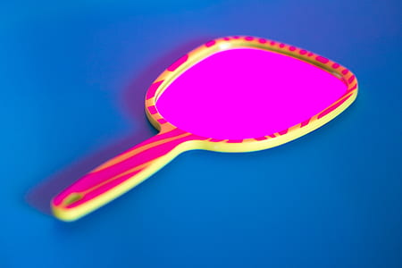pink and yellow handheld mirror on blue surface thumbnail
