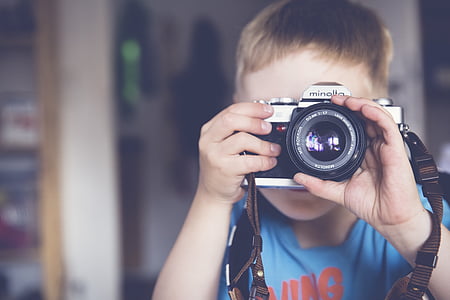 boy holding silver Minolta DSLR camera thumbnail