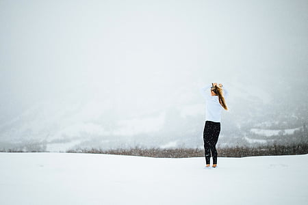 woman in white long-sleeved shirt and black pants outfit standing in the middle of snow at daytime thumbnail