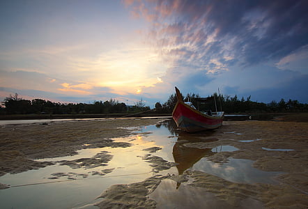 brown and orange wooden boat on wet sand during daytime thumbnail