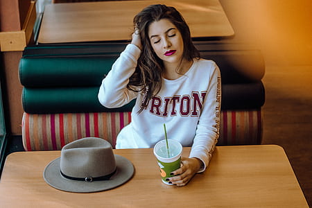 woman sitting on bench while holding disposable cup thumbnail