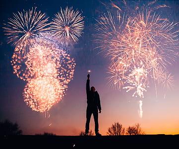 person raising lighted sparkle with fireworks on sky during nighttime thumbnail