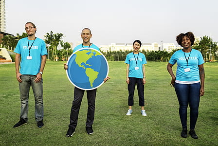 Group of Four People Wearing Blue Standing on Green Grass Field thumbnail