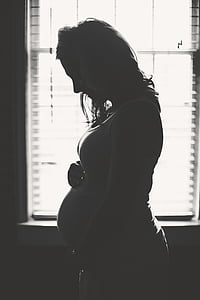 grayscale photography of pregnant woman touching her tummy thumbnail