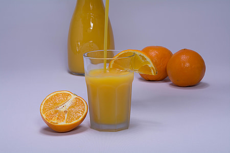 orange juice-filled drinking glass beside orange fruit slice thumbnail